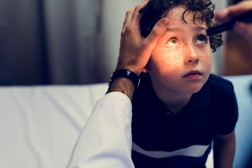 Medical professional checking young boys eyes for concussion 