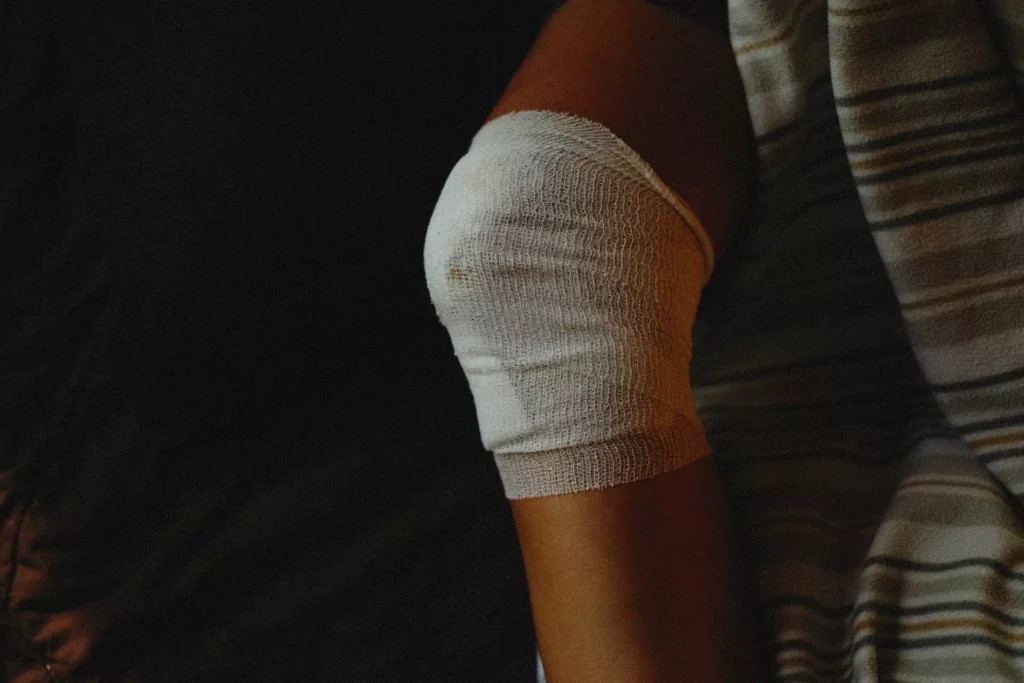 A person with a bandaged knee lying on a bed, possibly recovering from an injury or surgery.