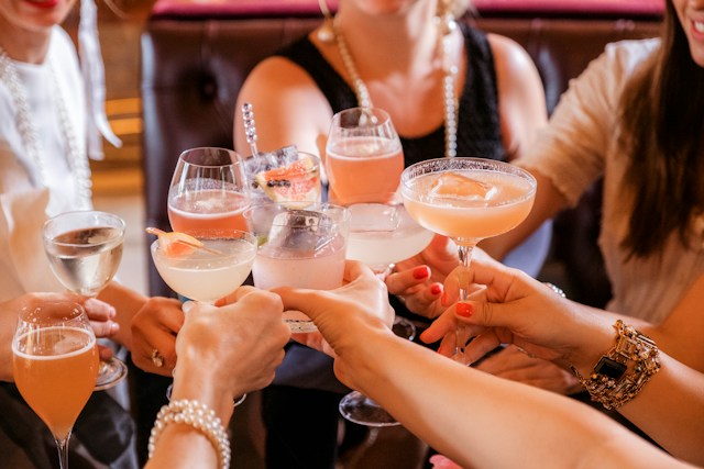 A lively group of women clinking glasses, celebrating with drinks in hand. 