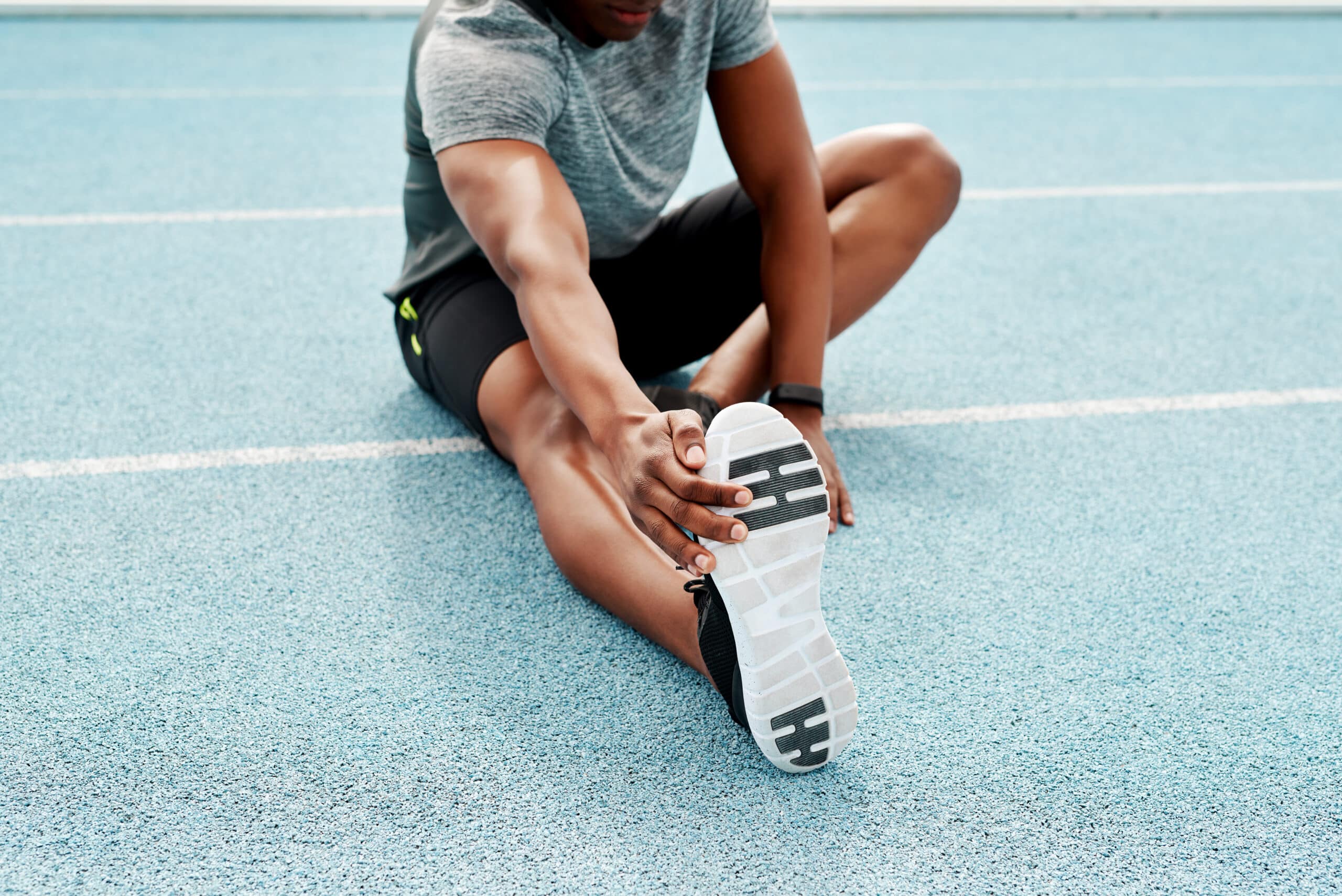 young male athlete stretching a cramping leg