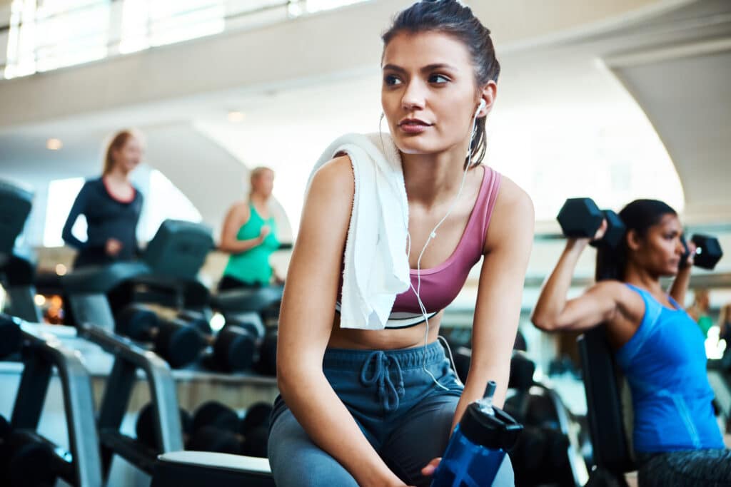 fitness centre scene with young woman in the foreground looking pensive
