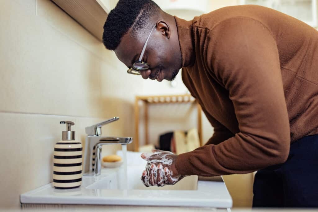 Adult man, happily cleaning the palms of his hands, in the bathroom.