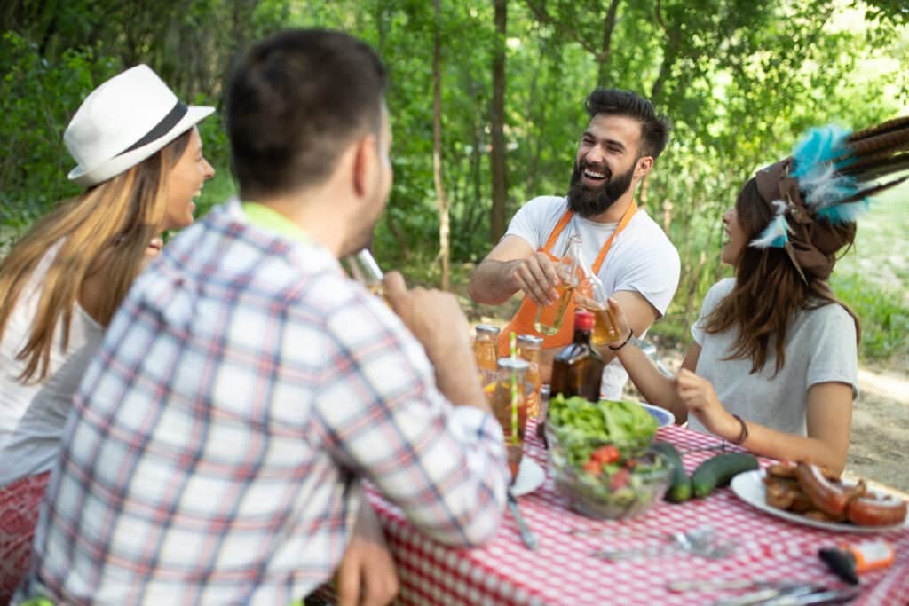 Happy friends camping and having a barbecue in nature