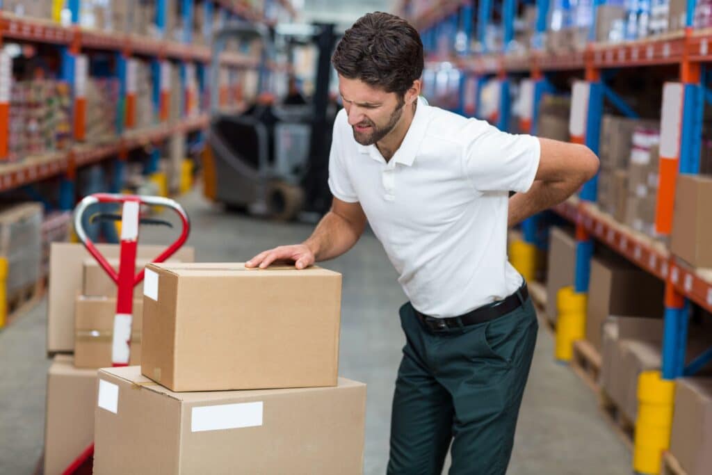 Red pallet jack lifting cardboard boxes on blue and red shelves in warehouse aisle, copy space. Industrial, logistics, organization, efficiency, labor, manual handling, professional