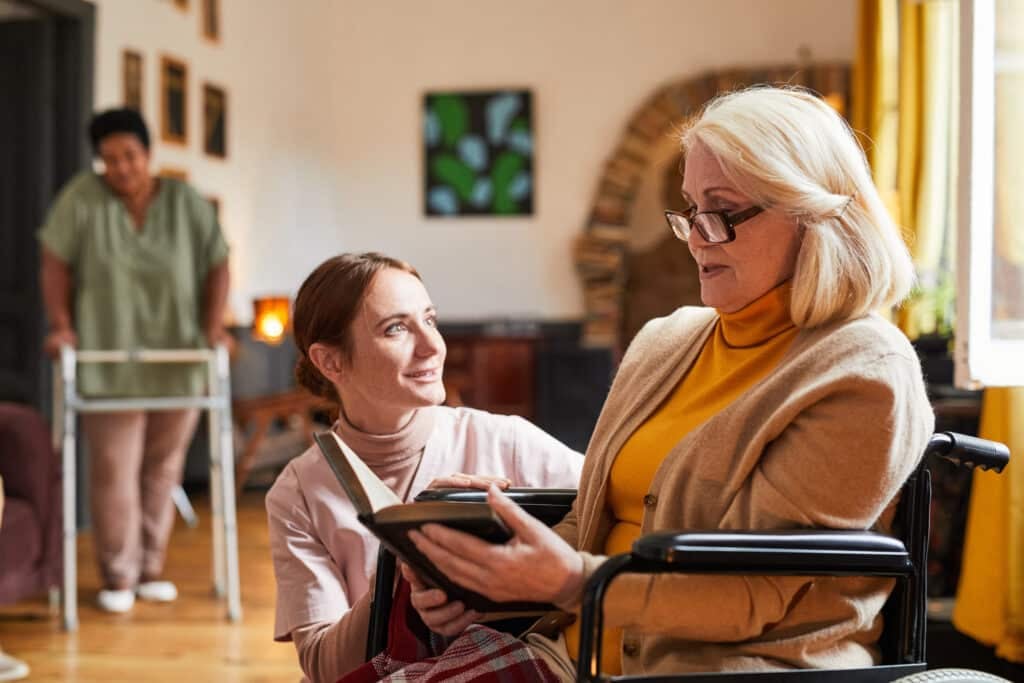 aged care worker - Portrait of young woman assisting senior woman in wheelchair at retirement home.