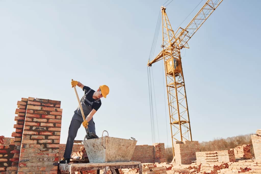 white card job - Using shovel. Construction worker in uniform and safety equipment have job on building.