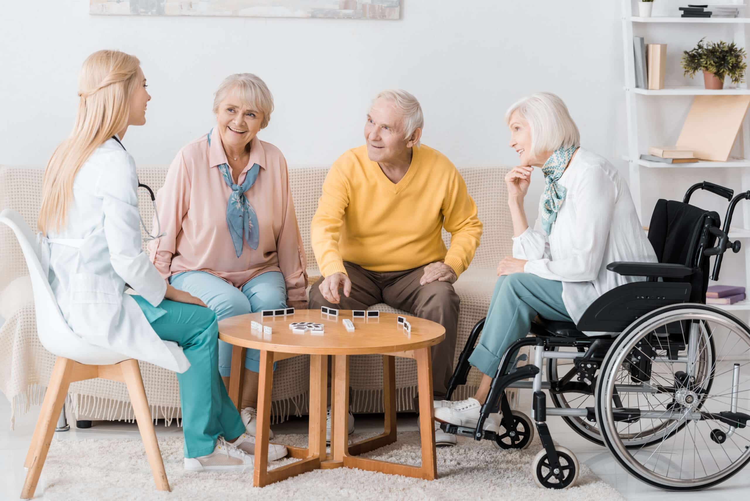 Aged Care - young female nurse playing domino with senior patients