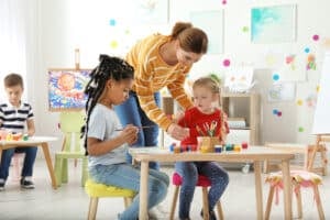 Early Childhood Educators’ Day 2026 - Children with female teacher at painting lesson indoors