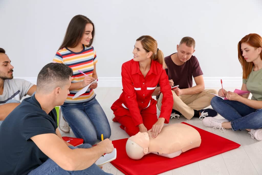 First aid training - Instructor demonstrating CPR on mannequin at first aid class indoors
