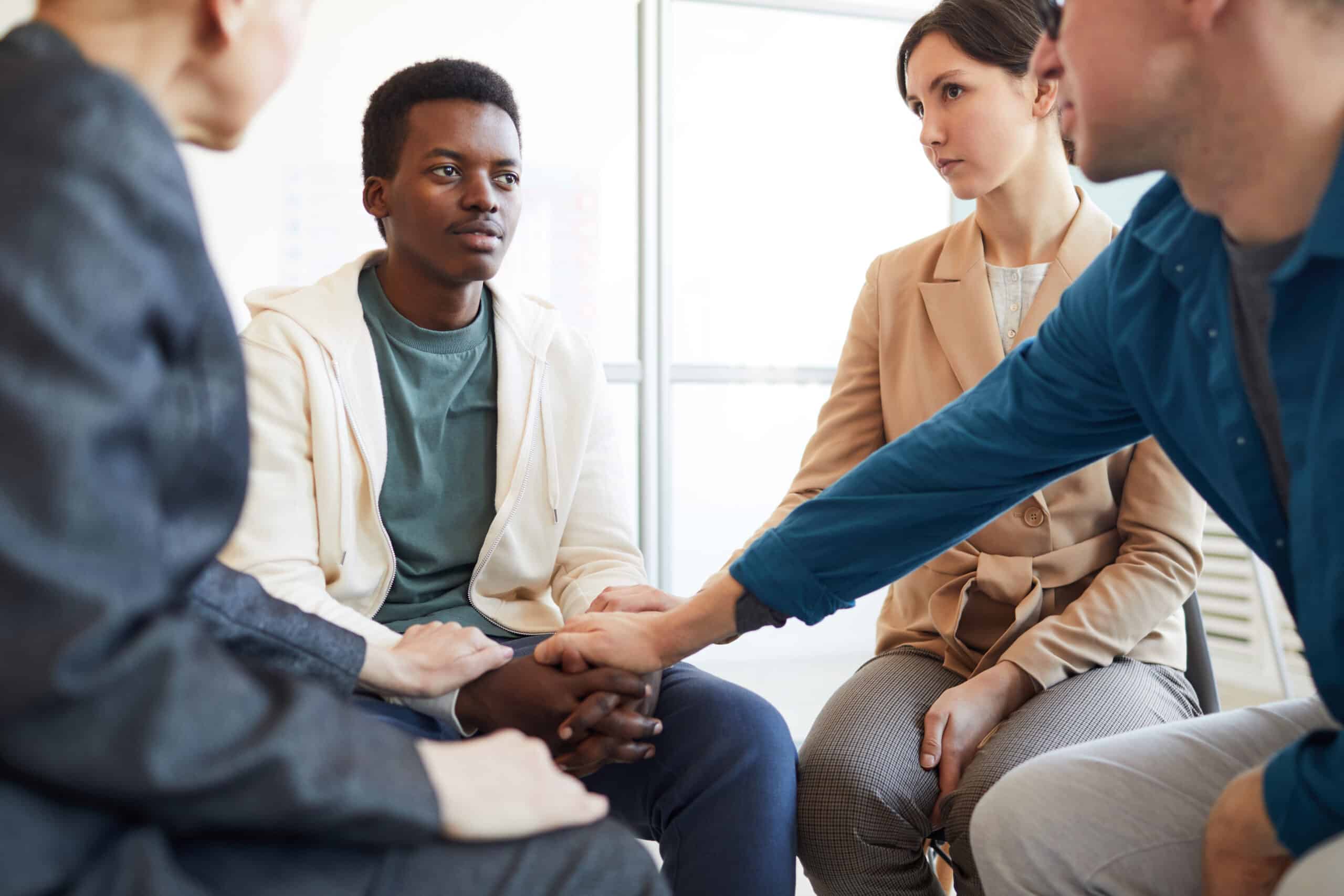 R U OK? Day - Multi-ethnic group of people holding hands while comforting African-American teenager in support group, copy space