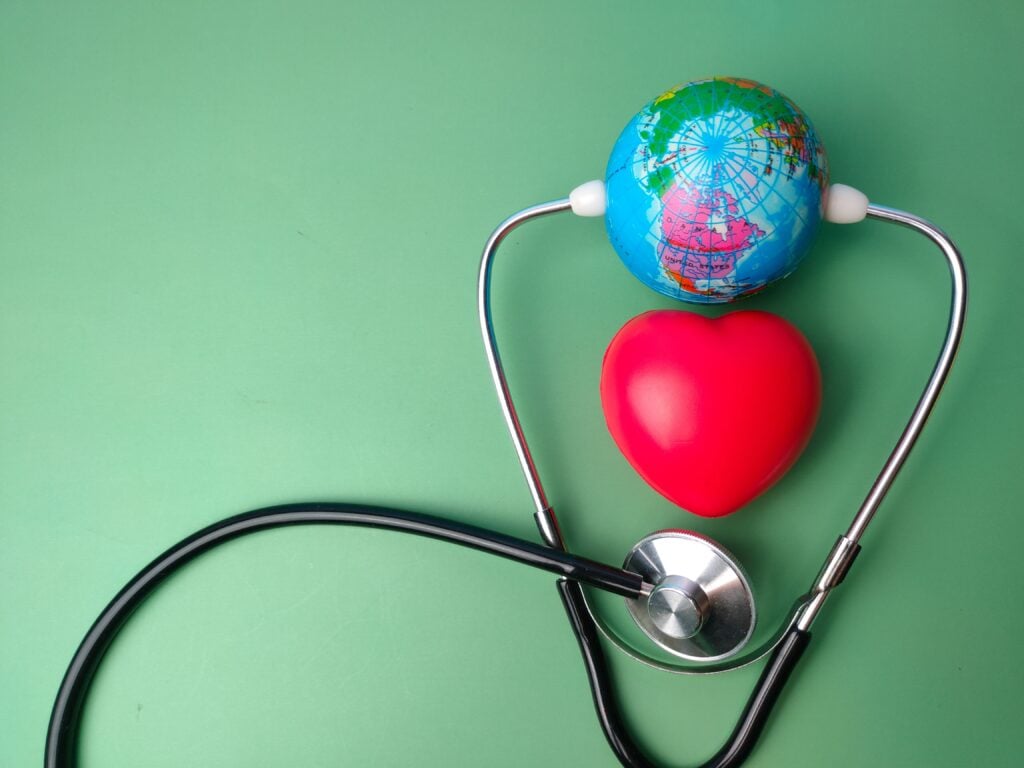 World Heart Day - A stethoscope, earth globe, and red heart on a green background